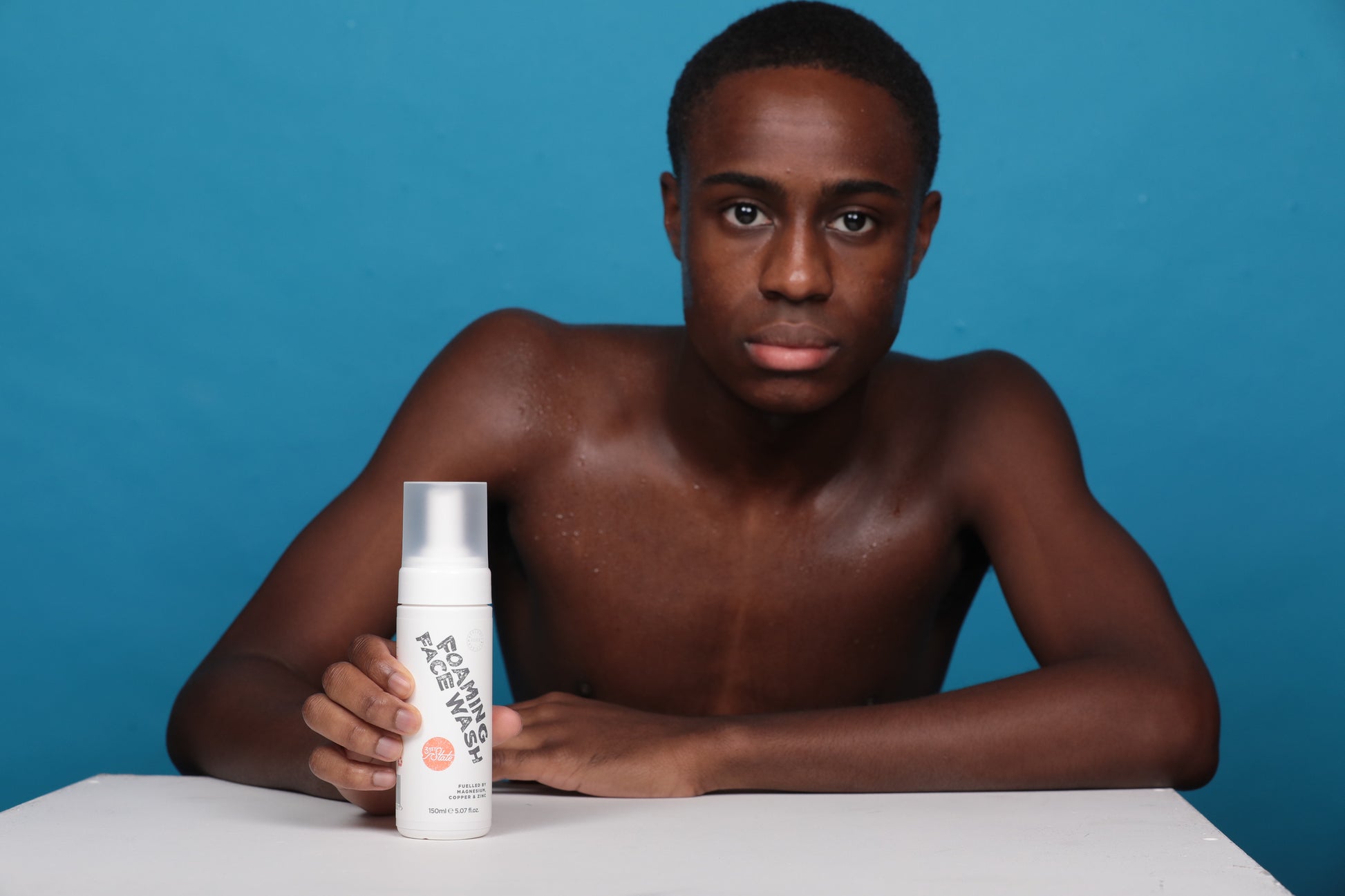 Teen boy holding 31st State Foaming Face Wash Bottle